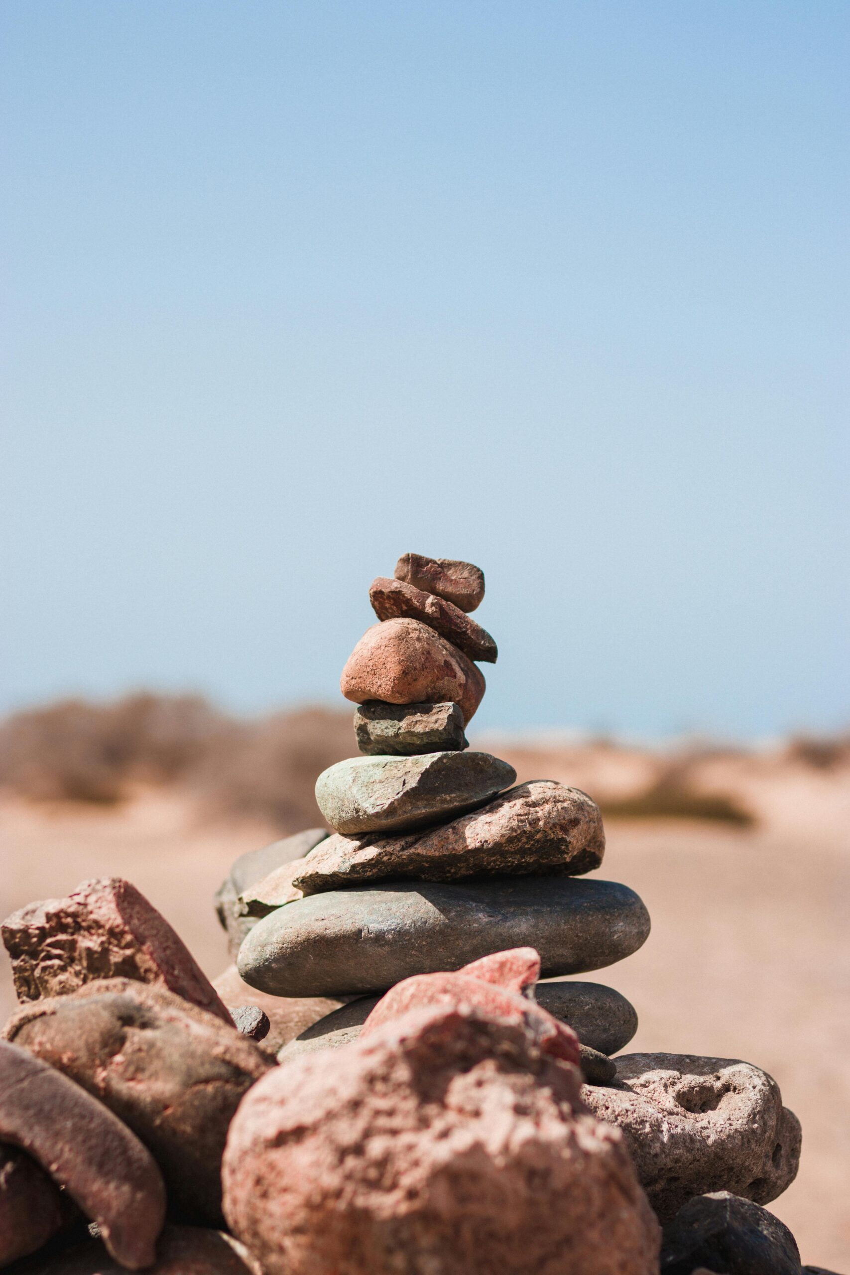 Balanced stack of stones on a sunny beach, symbolizing mindfulness, inner peace, and emotional stability