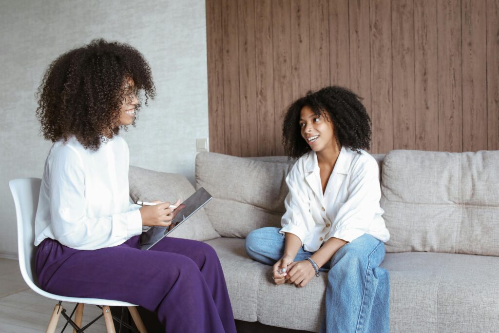 Two women in a friendly conversation on a sofa, showcasing a relaxed atmosphere.